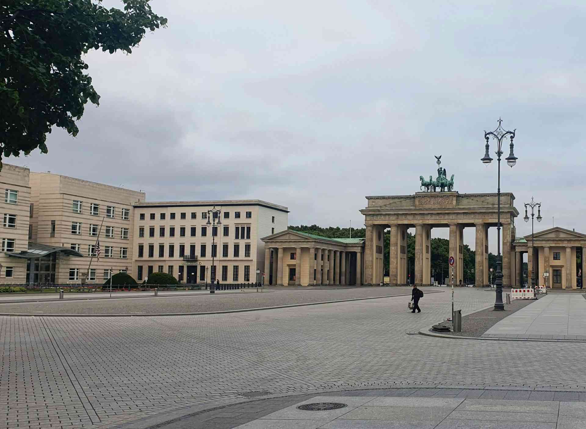 eine Person, die vor einem großen Gebäude entlanggeht