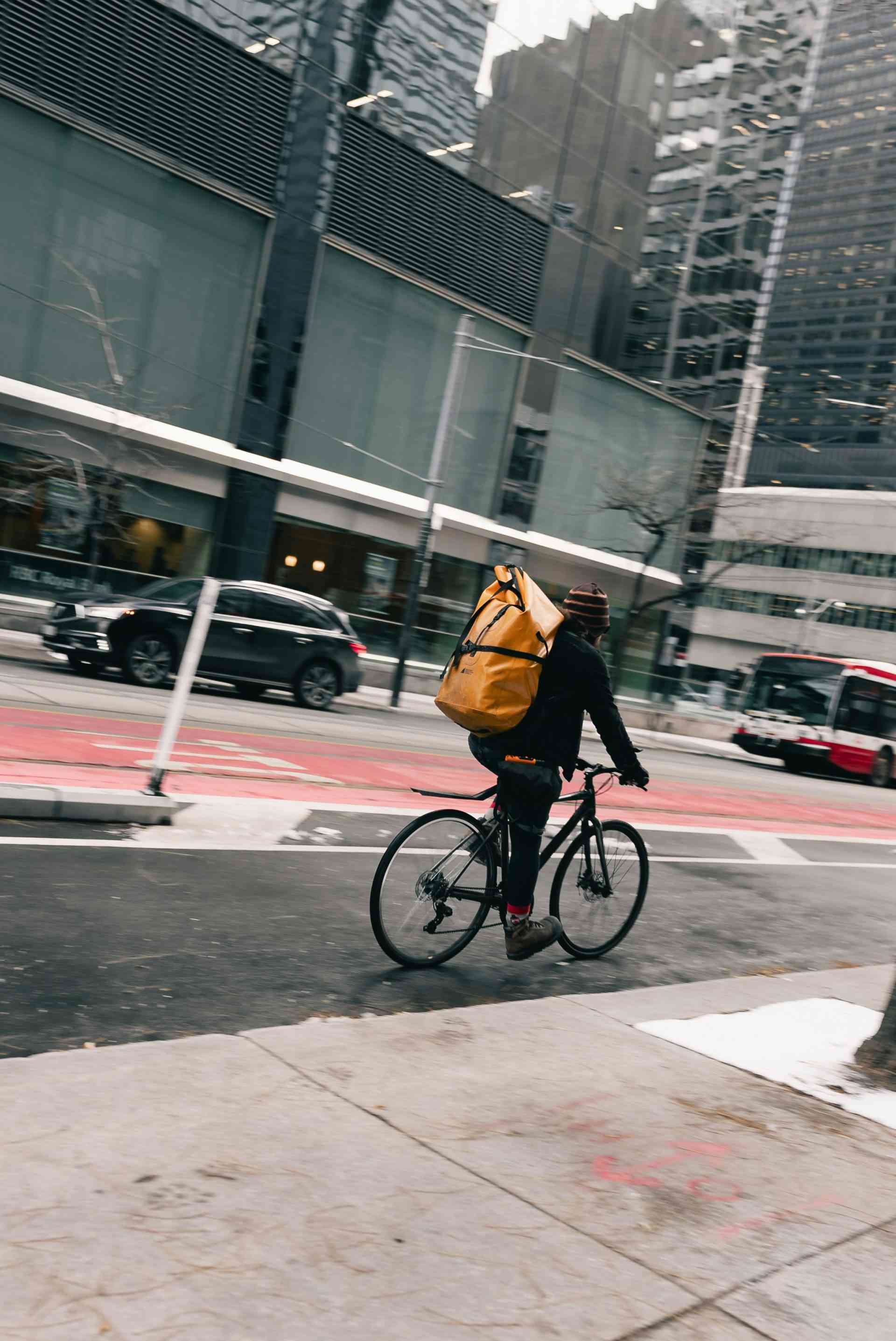 Radfahrer mit großer gelber Tasche navigiert durch die Stadtstraße